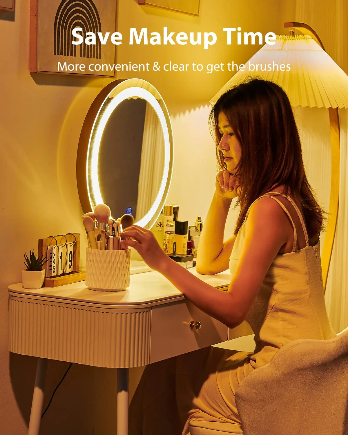 Woman at vanity with LED mirror organizing makeup brushes in ceramic holder