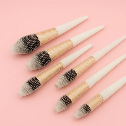 Set of six makeup brushes with wooden handles on a pink background
