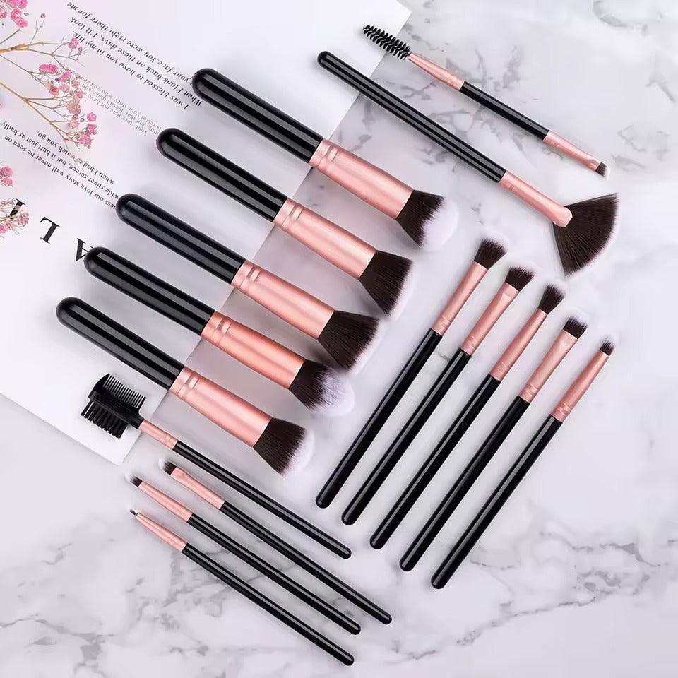 Set of black and rose gold makeup brushes arranged on marble background