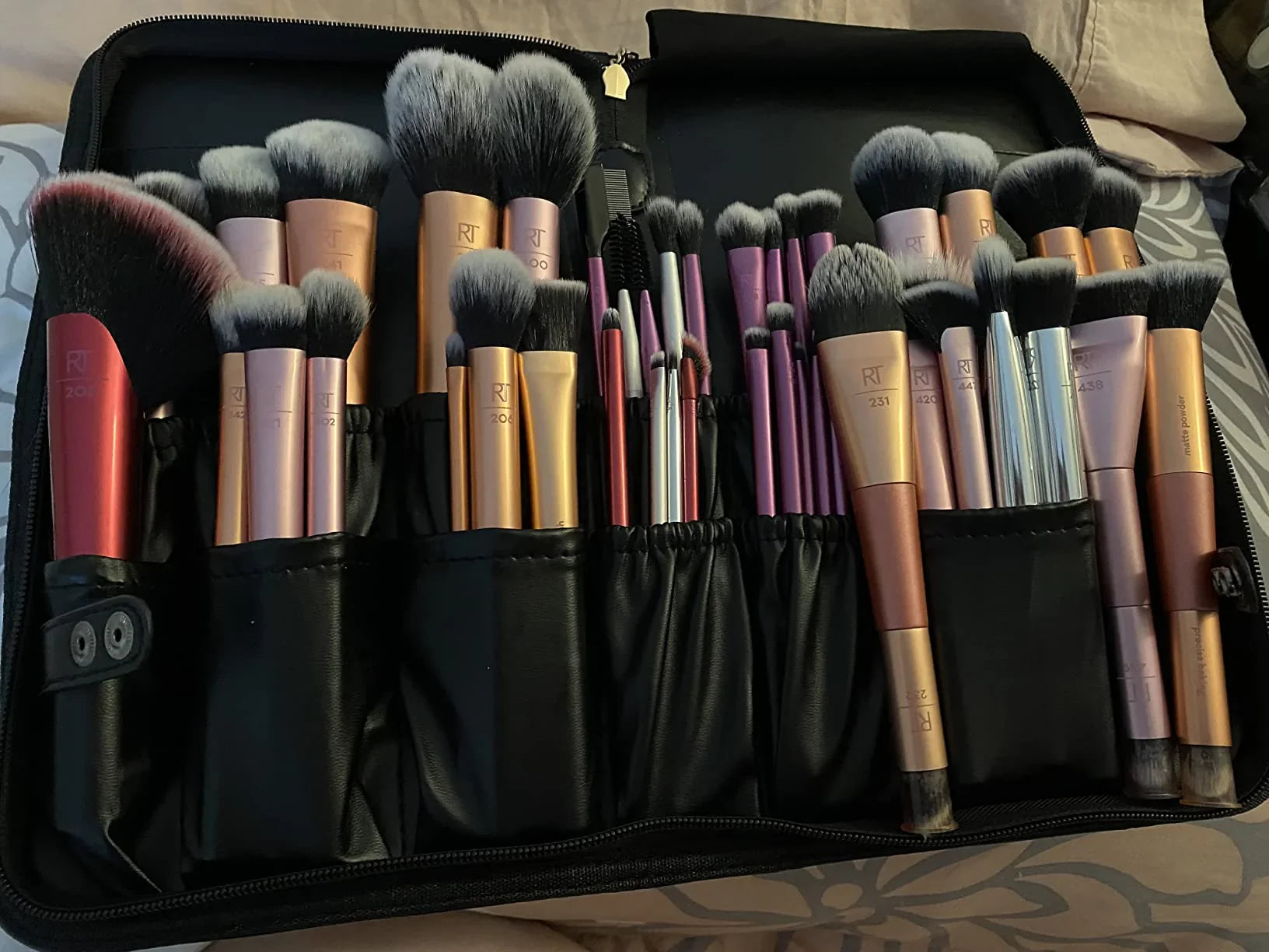 Set of makeup brushes in a black case on a patterned surface