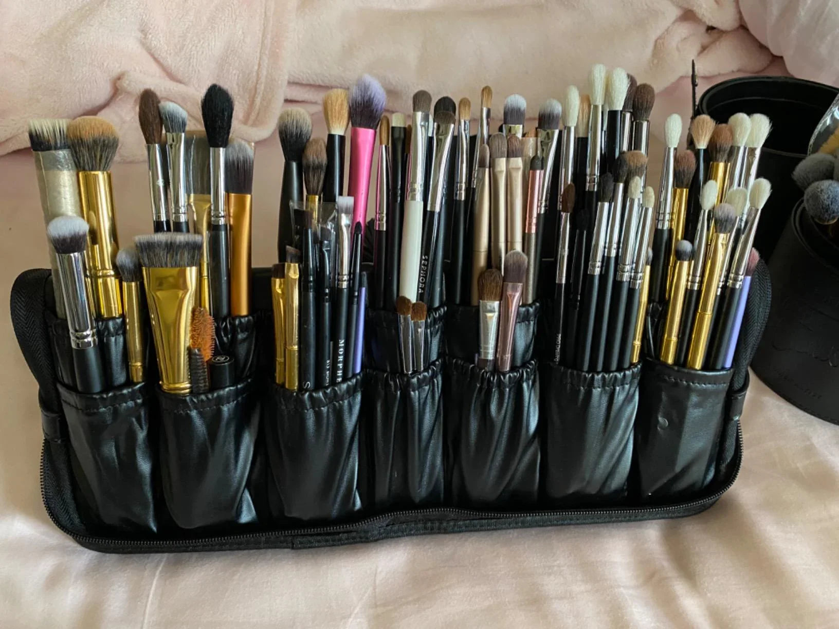 Set of makeup brushes in a black holder on a light-colored surface